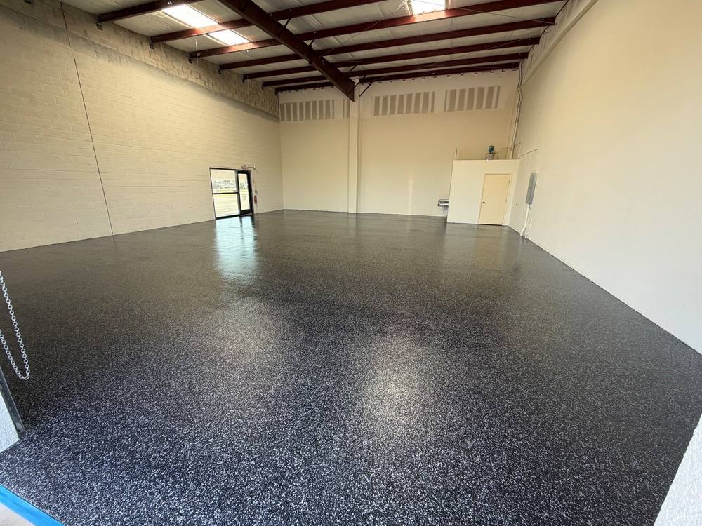 Dark flake floor in a commercial bay with a steel roof frame and cream block walls