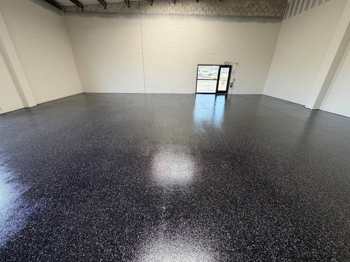 Dark flake floor in a bright commercial bay with a glass door at the back