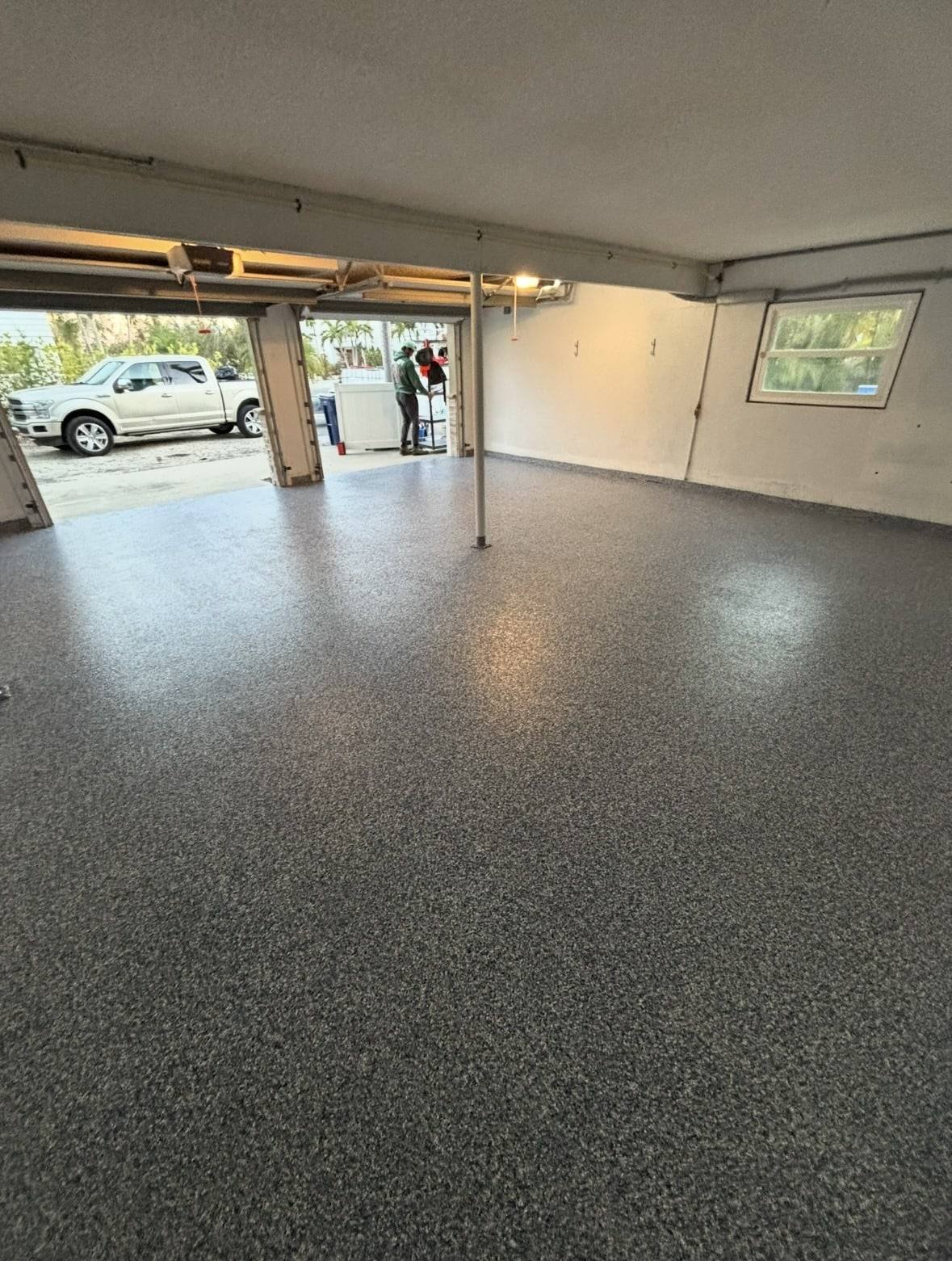 Dark gray flake floor in a garage with the door open to the driveway
