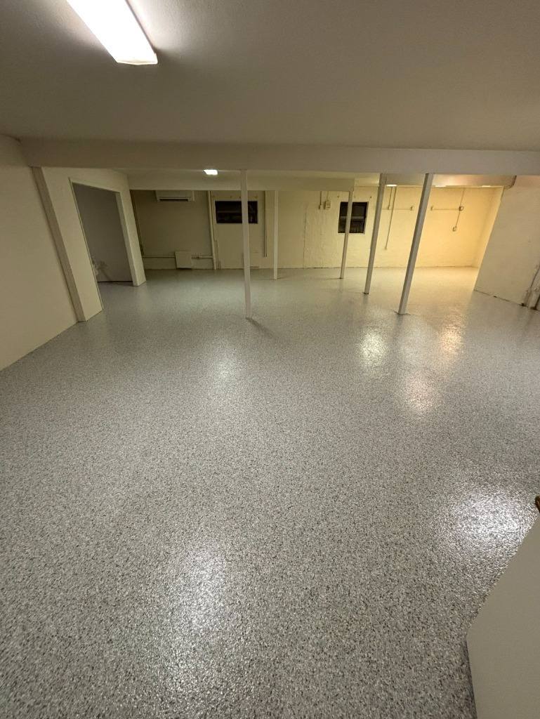 Light gray flake floor across a large basement room with white posts